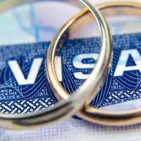 Macro photo of US entry visa sticker in a passport and a couple of rings. Conceptual photo for immigration. Selective focus.